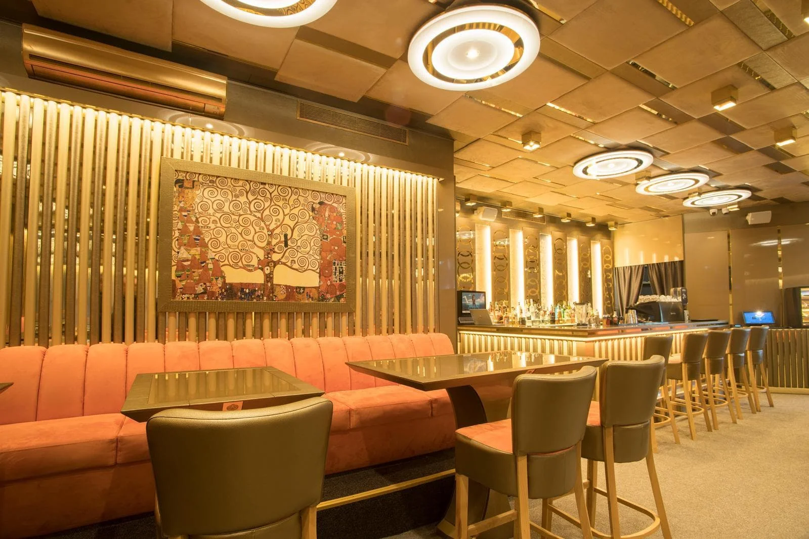 Барът на BLEND Bar & Dinner със златни ламели, картина и коралови сепарета