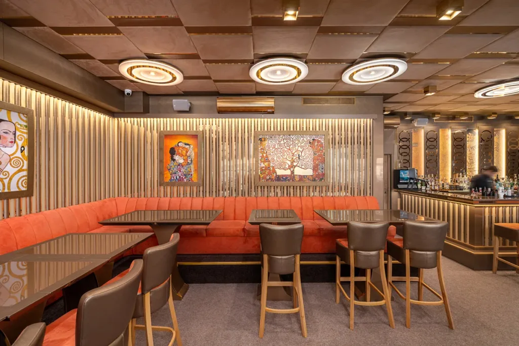 Лаундж зона с коралови дивани и латунени панели в BLEND Bar & Dinner